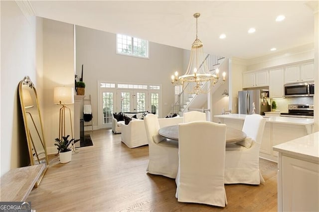 dining room featuring light hardwood / wood-style floors, french doors, a healthy amount of sunlight, and a notable chandelier