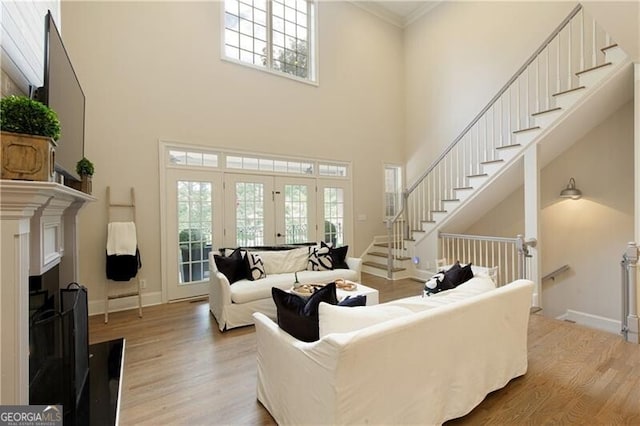 living room with light hardwood / wood-style flooring, a high ceiling, crown molding, and french doors