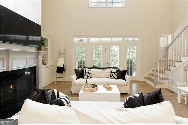 living room featuring a high ceiling, french doors, and light hardwood / wood-style floors