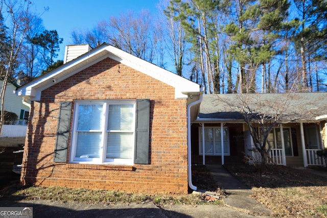 view of property exterior with brick siding and a chimney