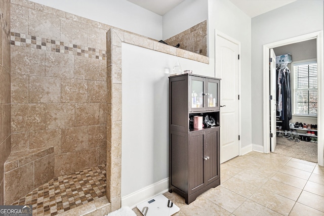 bathroom featuring a walk in shower, tile patterned floors, a walk in closet, and baseboards