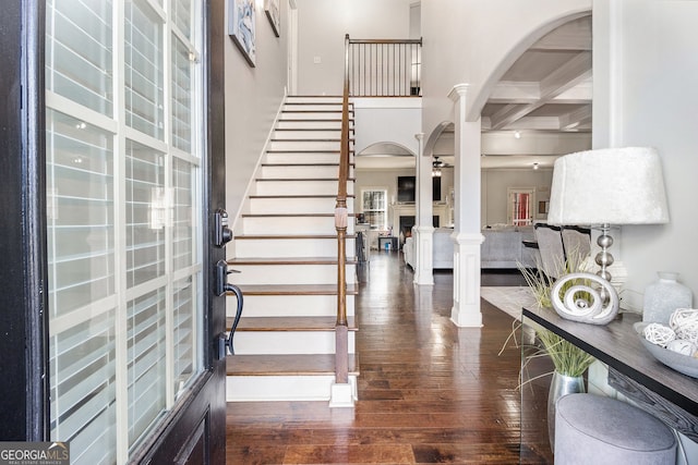 entryway with beam ceiling, dark wood-style flooring, decorative columns, a fireplace, and coffered ceiling