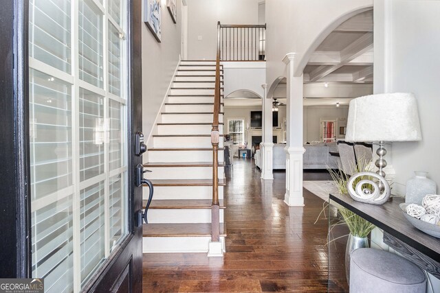 224 Jester Ct, Mcdonough, GA 30252 - entrance foyer featuring a high ceiling, arched walkways, dark wood finished floors, stairs, and ornate columns