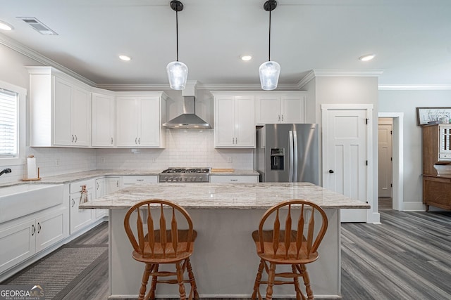 kitchen with a center island, stainless steel refrigerator with ice dispenser, visible vents, white cabinetry, and wall chimney exhaust hood