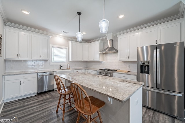 kitchen with appliances with stainless steel finishes, white cabinetry, and wall chimney range hood