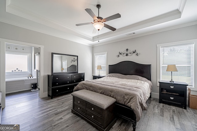 bedroom featuring ornamental molding, a raised ceiling, visible vents, and wood finished floors