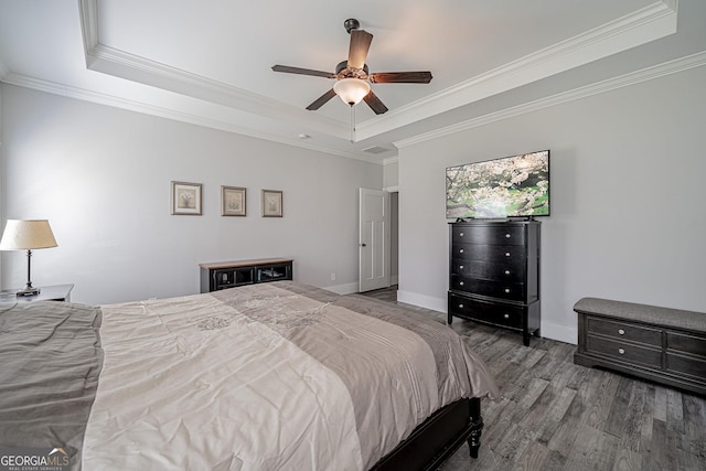 bedroom with baseboards, a tray ceiling, wood finished floors, and crown molding