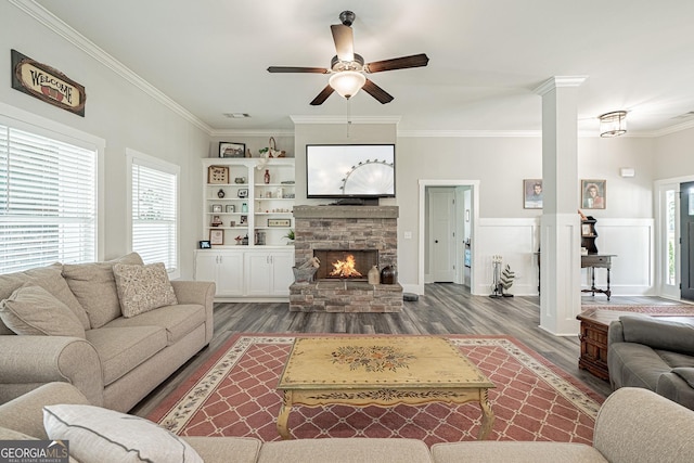 living area with ceiling fan, wood finished floors, crown molding, ornate columns, and a fireplace