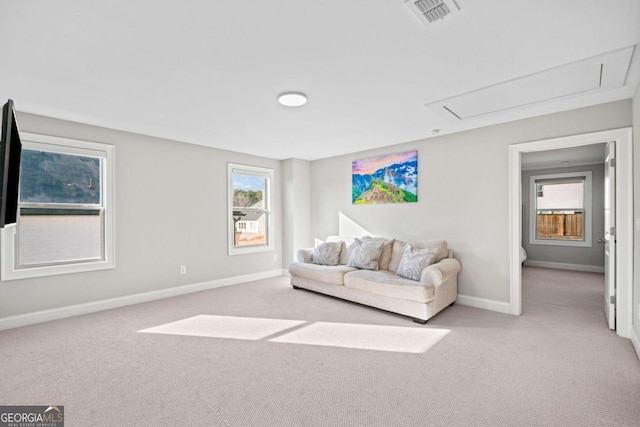 living area featuring plenty of natural light, visible vents, baseboards, and light colored carpet