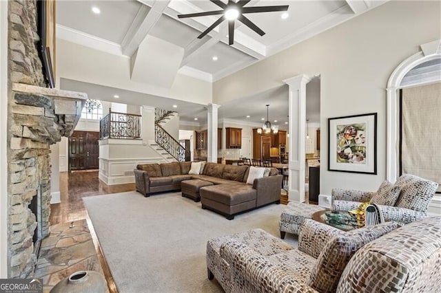 living room with beam ceiling, a high ceiling, coffered ceiling, ceiling fan with notable chandelier, and ornate columns