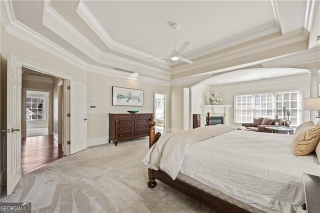 carpeted bedroom featuring a tray ceiling, ceiling fan, and crown molding