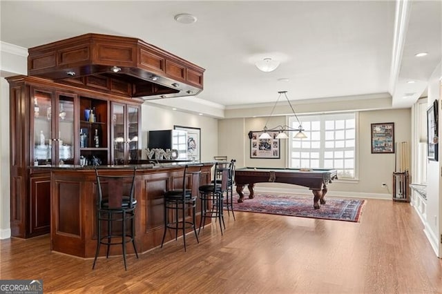 bar featuring hanging light fixtures, crown molding, and hardwood / wood-style floors