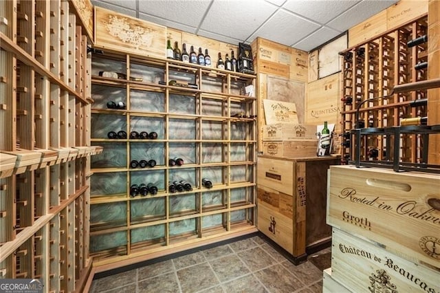 wine cellar featuring a drop ceiling and wood walls