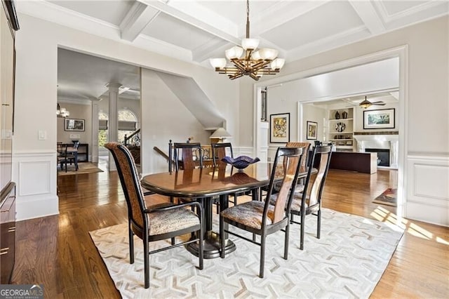 dining space with ceiling fan with notable chandelier, coffered ceiling, light hardwood / wood-style flooring, and beamed ceiling