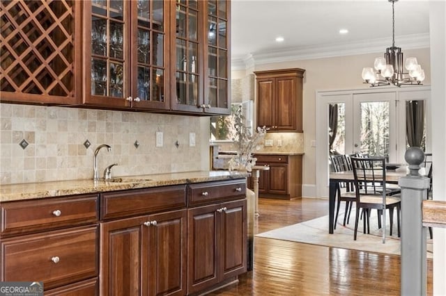 kitchen featuring sink, light stone counters, hanging light fixtures, and plenty of natural light