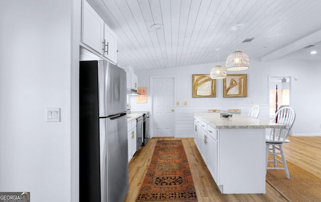 kitchen featuring light countertops, visible vents, freestanding refrigerator, a kitchen island, and a kitchen breakfast bar