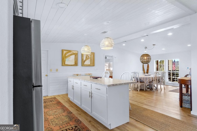 kitchen with wooden ceiling, light wood-style flooring, white cabinets, and freestanding refrigerator