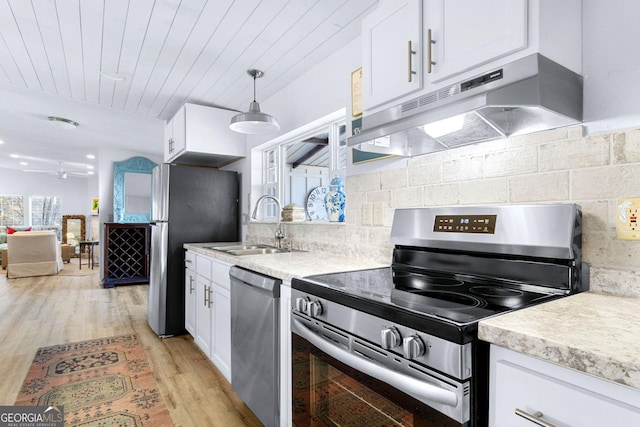 kitchen featuring appliances with stainless steel finishes, white cabinets, a sink, light wood-type flooring, and under cabinet range hood