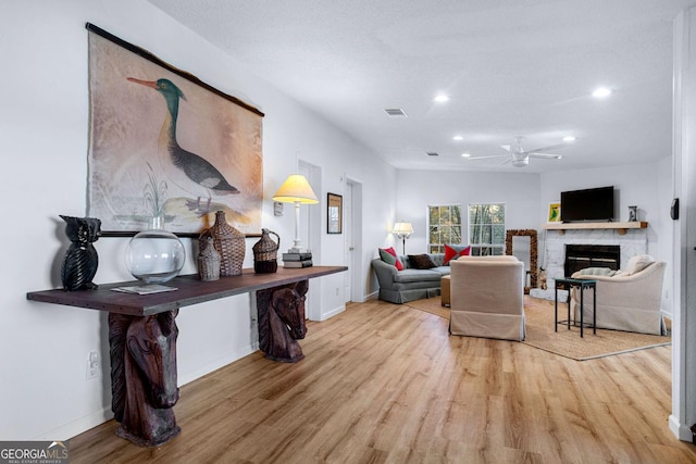 living area featuring baseboards, visible vents, wood finished floors, a stone fireplace, and recessed lighting