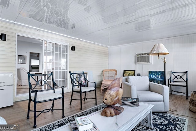 living area featuring a wall unit AC and wood finished floors