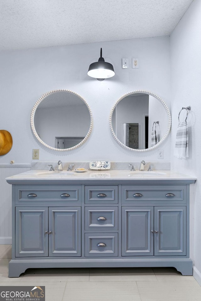 bathroom with a sink, a textured ceiling, and double vanity