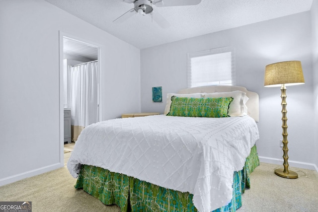 carpeted bedroom featuring a textured ceiling, connected bathroom, a ceiling fan, and baseboards