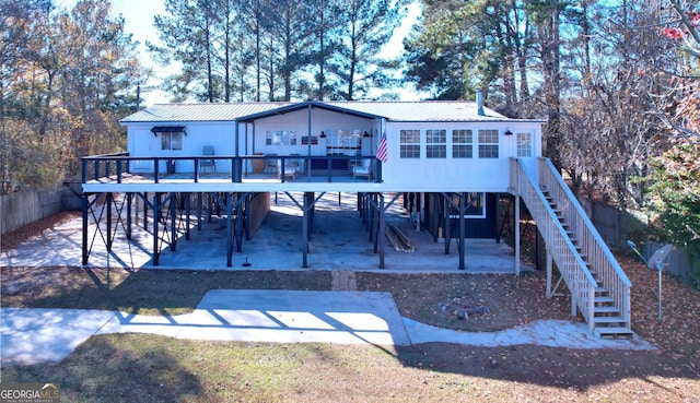 back of property with a patio area, metal roof, a wooden deck, and stairs