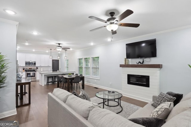 living room with ornamental molding, dark wood-type flooring, and ceiling fan