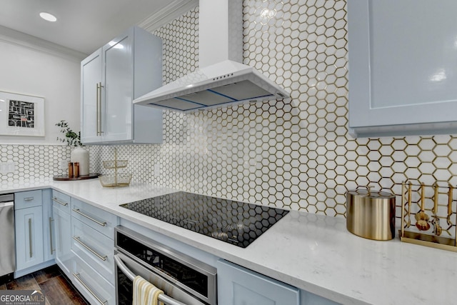 kitchen with light stone counters, backsplash, appliances with stainless steel finishes, and wall chimney range hood