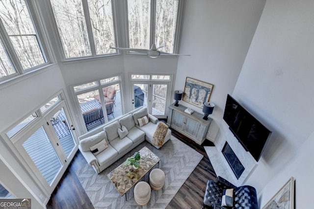 living room with a wealth of natural light, wood finished floors, and a towering ceiling