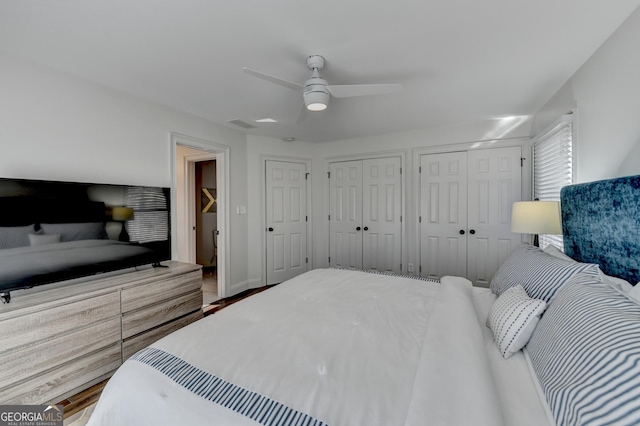 bedroom with two closets, wood finished floors, and ceiling fan