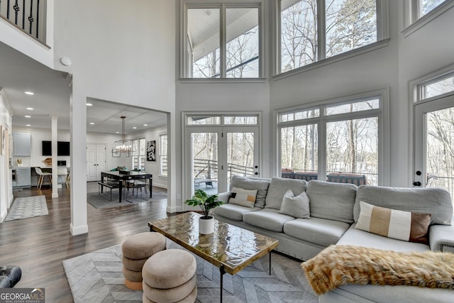 living room with recessed lighting, dark wood-style flooring, a high ceiling, and a notable chandelier