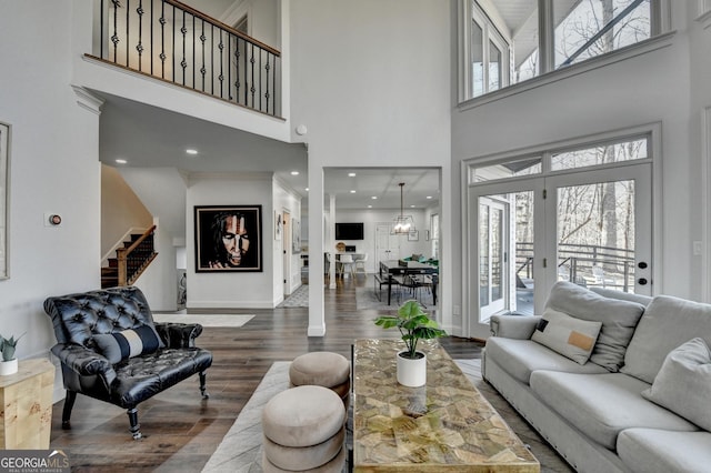 living room with stairway, a high ceiling, a wealth of natural light, and wood finished floors