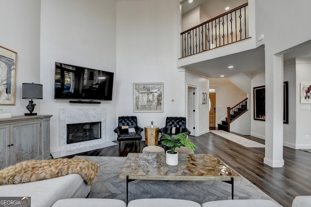 living area featuring baseboards, wood finished floors, a high ceiling, stairs, and a fireplace