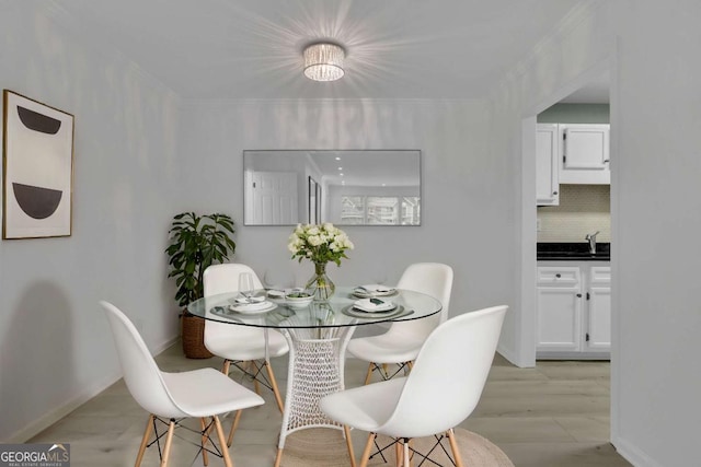 dining space featuring ornamental molding and light hardwood / wood-style floors