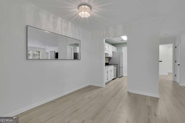 unfurnished living room featuring ornamental molding and light hardwood / wood-style flooring