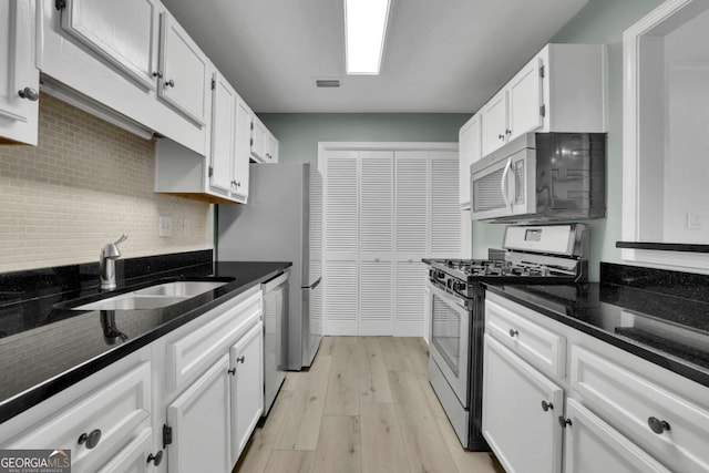 kitchen with sink, dark stone countertops, white cabinets, and stainless steel appliances