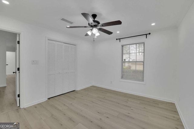 unfurnished bedroom with ceiling fan, light wood-type flooring, and a closet