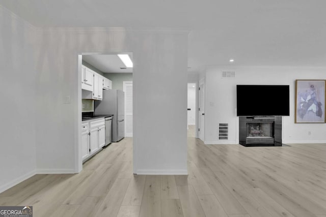 kitchen featuring ornamental molding, stainless steel appliances, white cabinets, and light hardwood / wood-style flooring