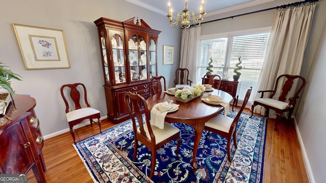 dining room featuring crown molding, a chandelier, and light hardwood / wood-style flooring