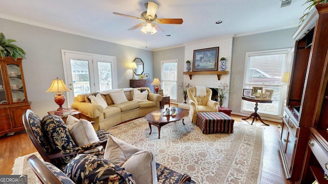 living room with ceiling fan, ornamental molding, a brick fireplace, and light hardwood / wood-style flooring