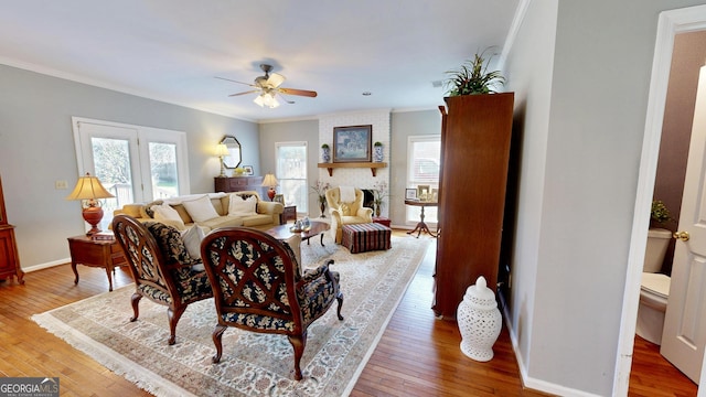 dining space featuring a fireplace, a healthy amount of sunlight, crown molding, and hardwood / wood-style floors