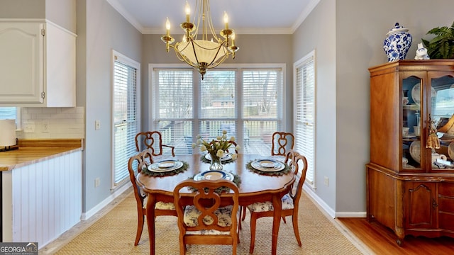 dining area with a notable chandelier, light wood-type flooring, and ornamental molding