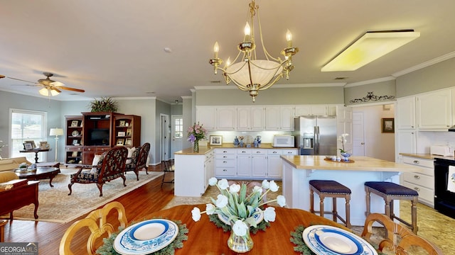 dining area with hardwood / wood-style floors, crown molding, and ceiling fan with notable chandelier