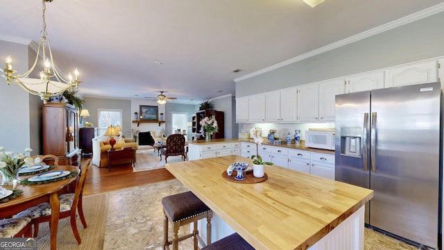 kitchen featuring hanging light fixtures, stainless steel fridge with ice dispenser, white cabinets, and crown molding