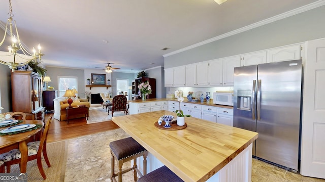 kitchen with kitchen peninsula, hanging light fixtures, white cabinets, and stainless steel fridge with ice dispenser