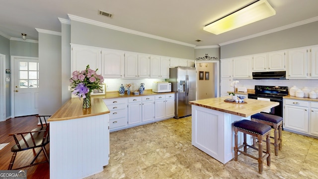 kitchen featuring a center island, a kitchen bar, butcher block counters, and white cabinets