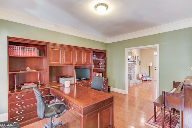 office space with baseboards, a stone fireplace, light wood-style flooring, and crown molding