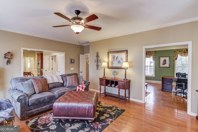 living area featuring light wood-style flooring, baseboards, ceiling fan, and crown molding