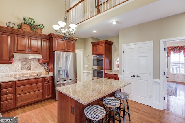 kitchen featuring appliances with stainless steel finishes, light wood-style floors, a center island, and under cabinet range hood